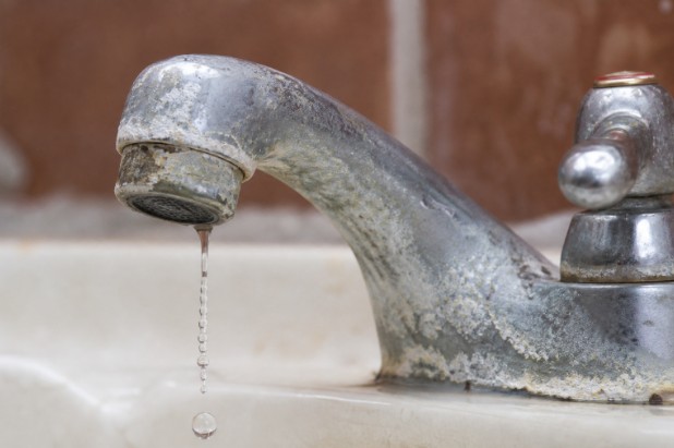 Leaky faucet with visible mineral buildup around spout and base.