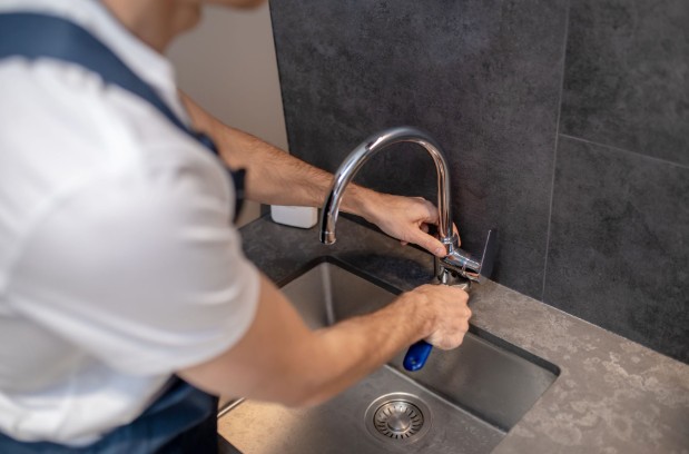 Leaky faucet repair with plumber replacing internal faucet parts.
