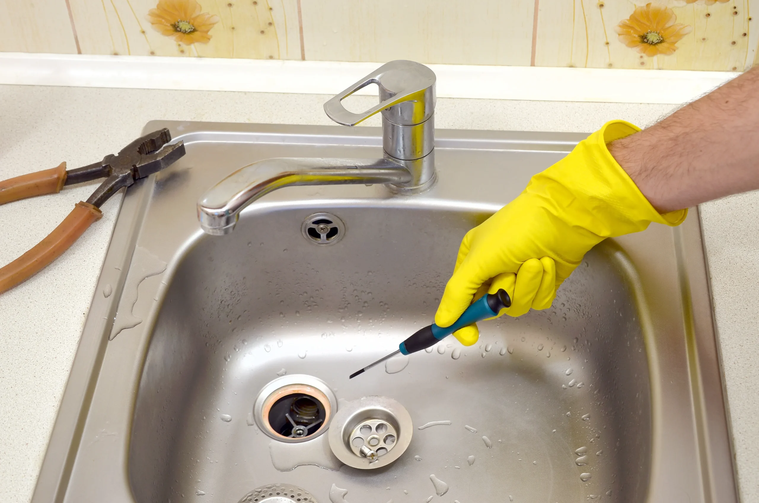 Plumbing services removing and repairing a kitchen sink drain to prevent clogs and backups.