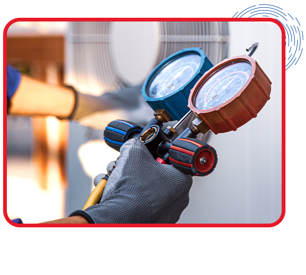 Close-up of a gloved hand holding HVAC gauges near an air conditioning unit, indicating maintenance in progress. The image conveys a sense of precision.