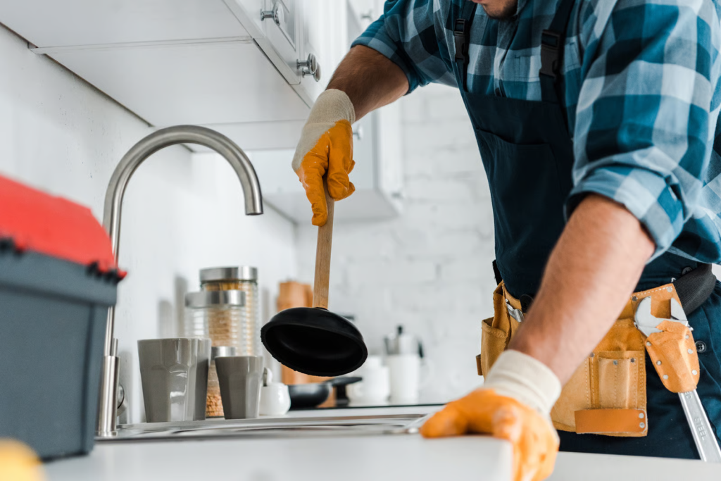 Plumbing services clearing a clogged kitchen sink drain.